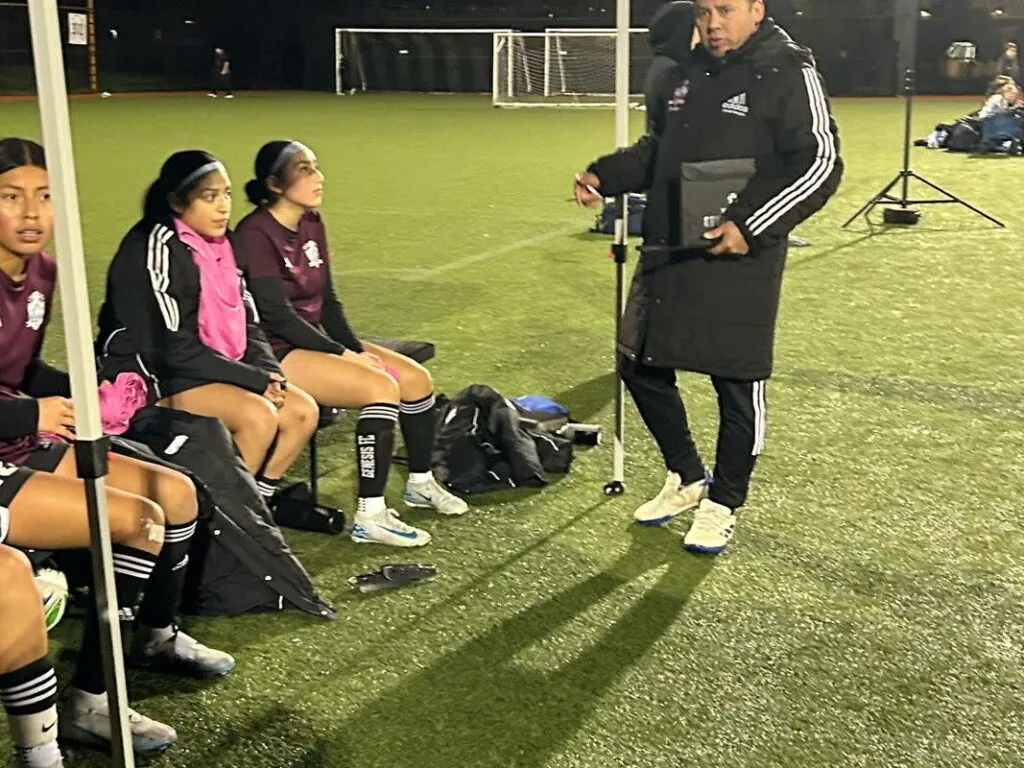 Genesis FC coach giving instructions to players on the sideline